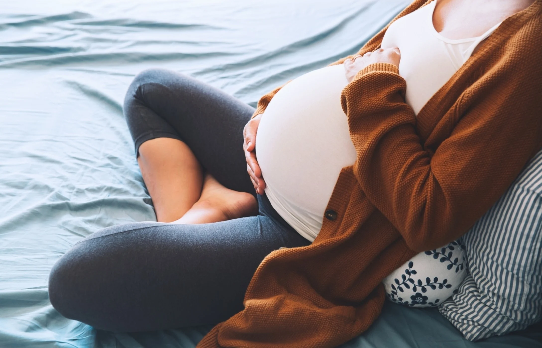 Pregnant mom hugs her belly in bed