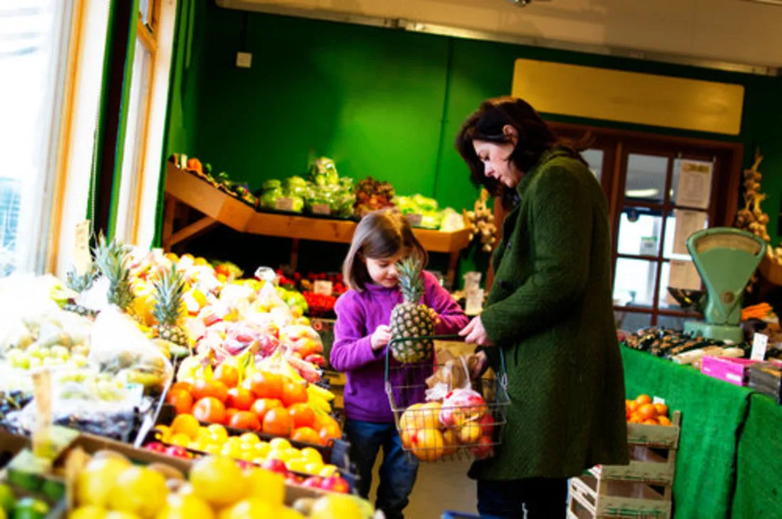 mom and daughter shopping in produce section of grocery store